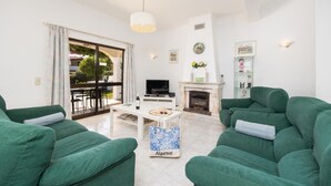 A living room with green sofas, a white coffee table, a fireplace, and a TV. - Villa Cavaco - Four Bedroom Villa, Sleeps 8 (Quarteira)
