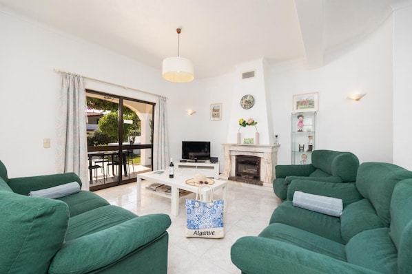 A living room with green sofas, a white coffee table, a fireplace, and a TV. - Villa Cavaco - Four Bedroom Villa, Sleeps 8 (Quarteira)