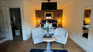 A modern living room with a sofa, a small round table with a vase, and a mirror on the wall.