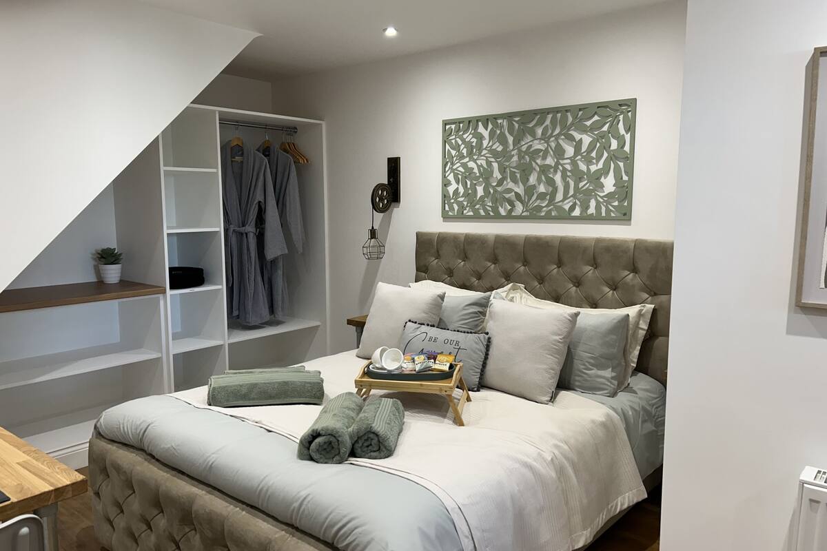 A bedroom with a bed, a wardrobe, a bedside table, and a decorative wall piece.