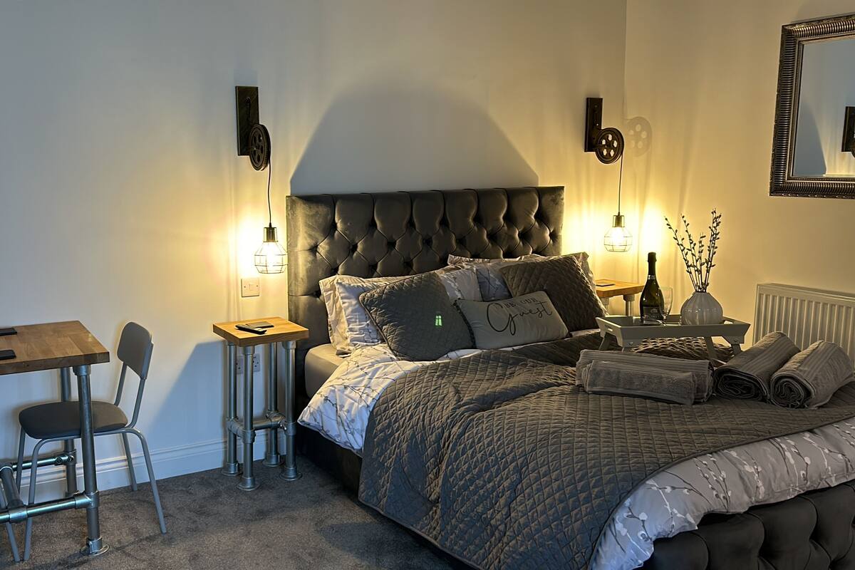 A bedroom with a bed, bedside table, lamp, and a small table with chairs.