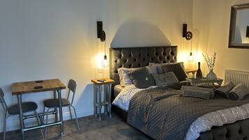 A bedroom with a bed, bedside table, lamp, and a small table with chairs.