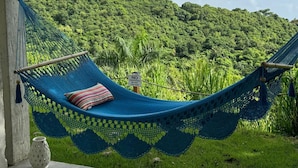 Un hamac avec un coussin à rayures, installé sur une colline verdoyante.