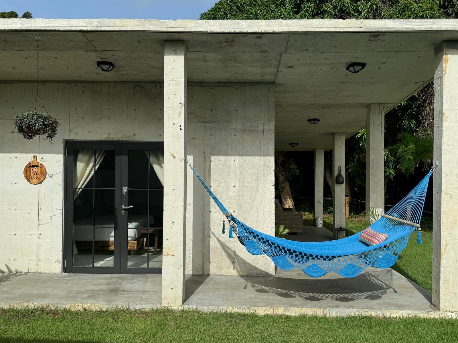 A concrete building with a hammock on the porch.
