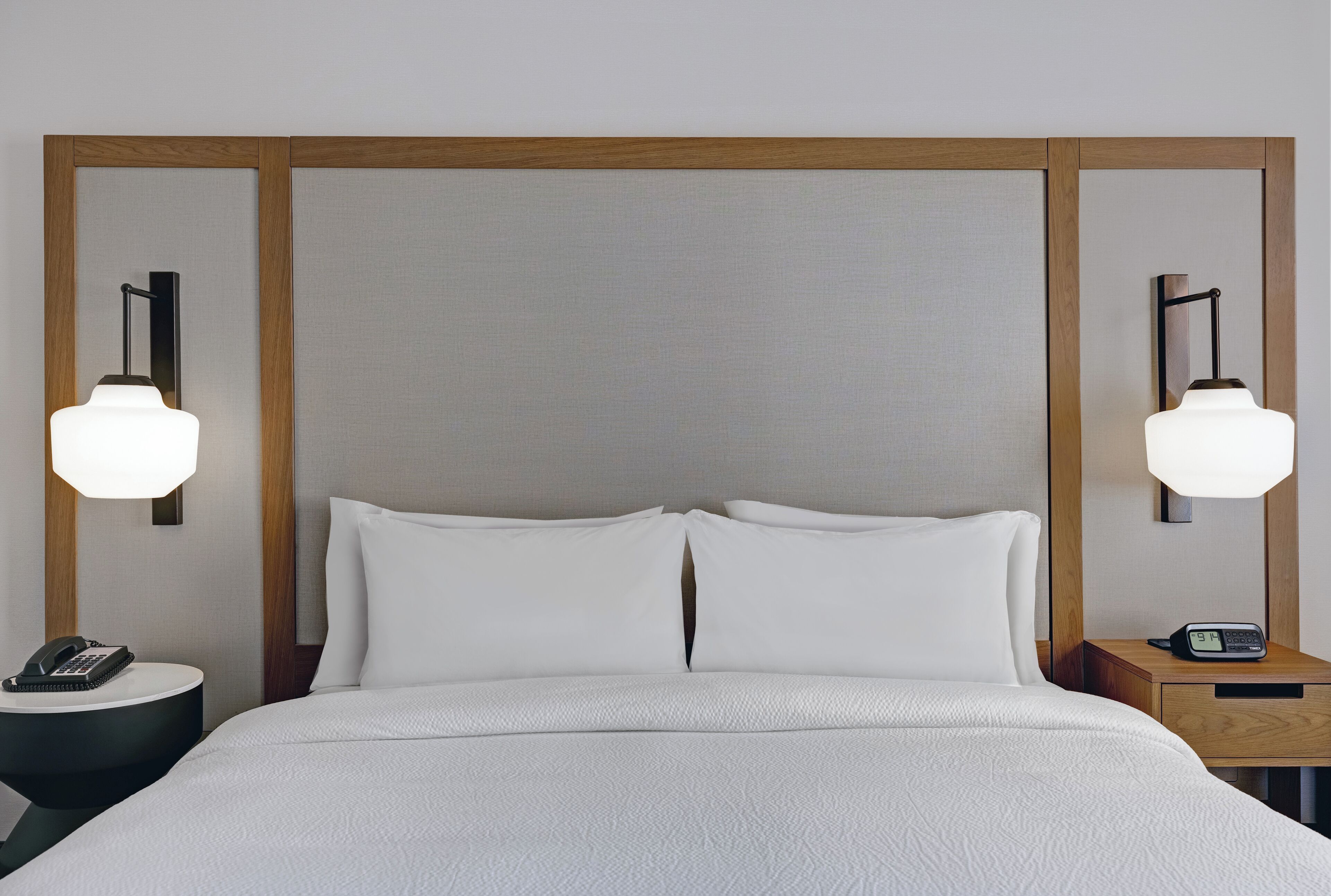 Ein Hotelzimmer mit einem großen Bett, zwei Nachttischen, einer Wandlampe und einem Beistelltisch.