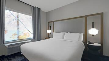Hotelkamer met een groot bed, een raam met gordijnen, een nachtkastje met een lamp en een bijzettafeltje met een telefoon.