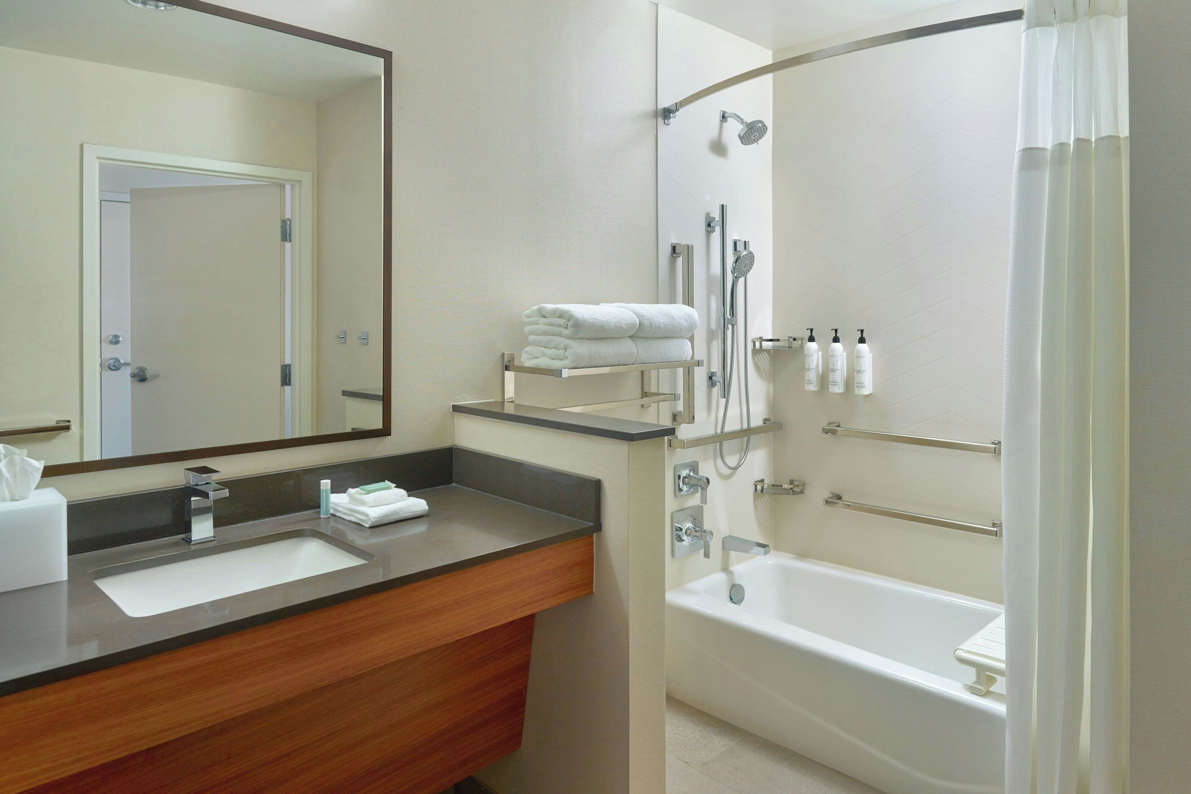 Een moderne badkamer met een wastafel, spiegel, douche en bad.