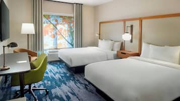 Habitación de hotel con dos camas, un escritorio con silla, televisión y ventana con cortinas.
