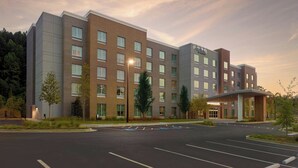 A multi-story hotel with a modern design, featuring a central entrance with a covered walkway, and a parking lot in front. - Fairfield Inn & Suites By Marriott Alpharetta Avalon Area (Alpharetta)