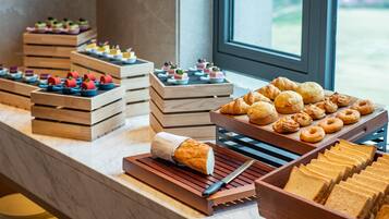 A buffet with various food items including pastries, bread, and desserts arranged on wooden trays.