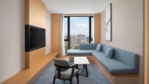 A modern hotel room with a large window, a flat-screen TV, a sofa, a chair, and a small table. - Fairfield By Marriott Chengdu Hi-Tech Zone (Chengdu)