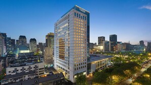 Un hôtel de grande hauteur au design moderne, entouré d’autres immeubles et donnant sur une rue animée.