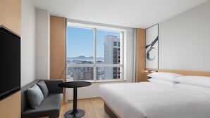 Une chambre d’hôtel moderne avec un grand lit, un canapé, une petite table et un téléviseur.