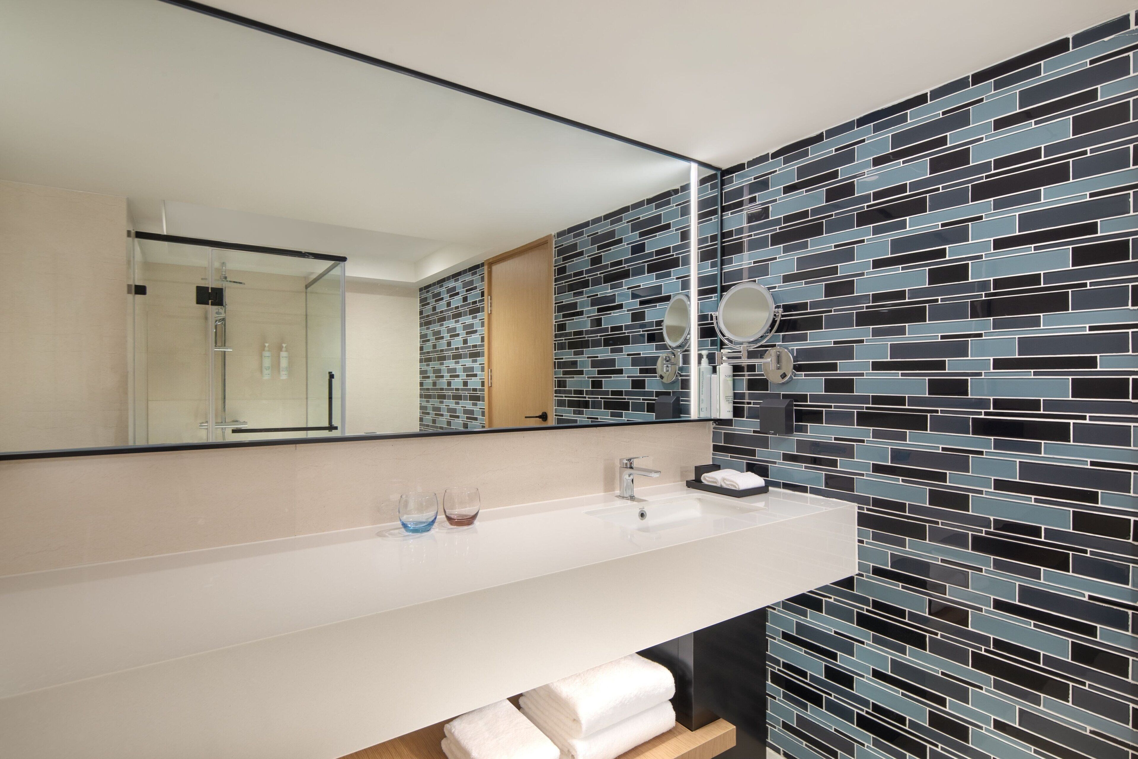 A modern bathroom with a white sink, a mirror, and a tiled backsplash.