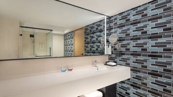 A modern bathroom with a white sink, a mirror, and a tiled backsplash.