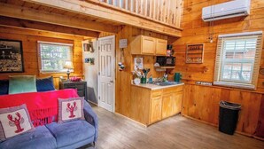 A cozy cabin interior with a living room, kitchenette, and a dining area.