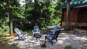 A rustic outdoor seating area with Adirondack chairs and a stone fire pit.
