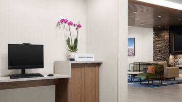A reception desk with a computer, a vase of orchids, and a sign reading "MARRIOTT BONVOGIO".