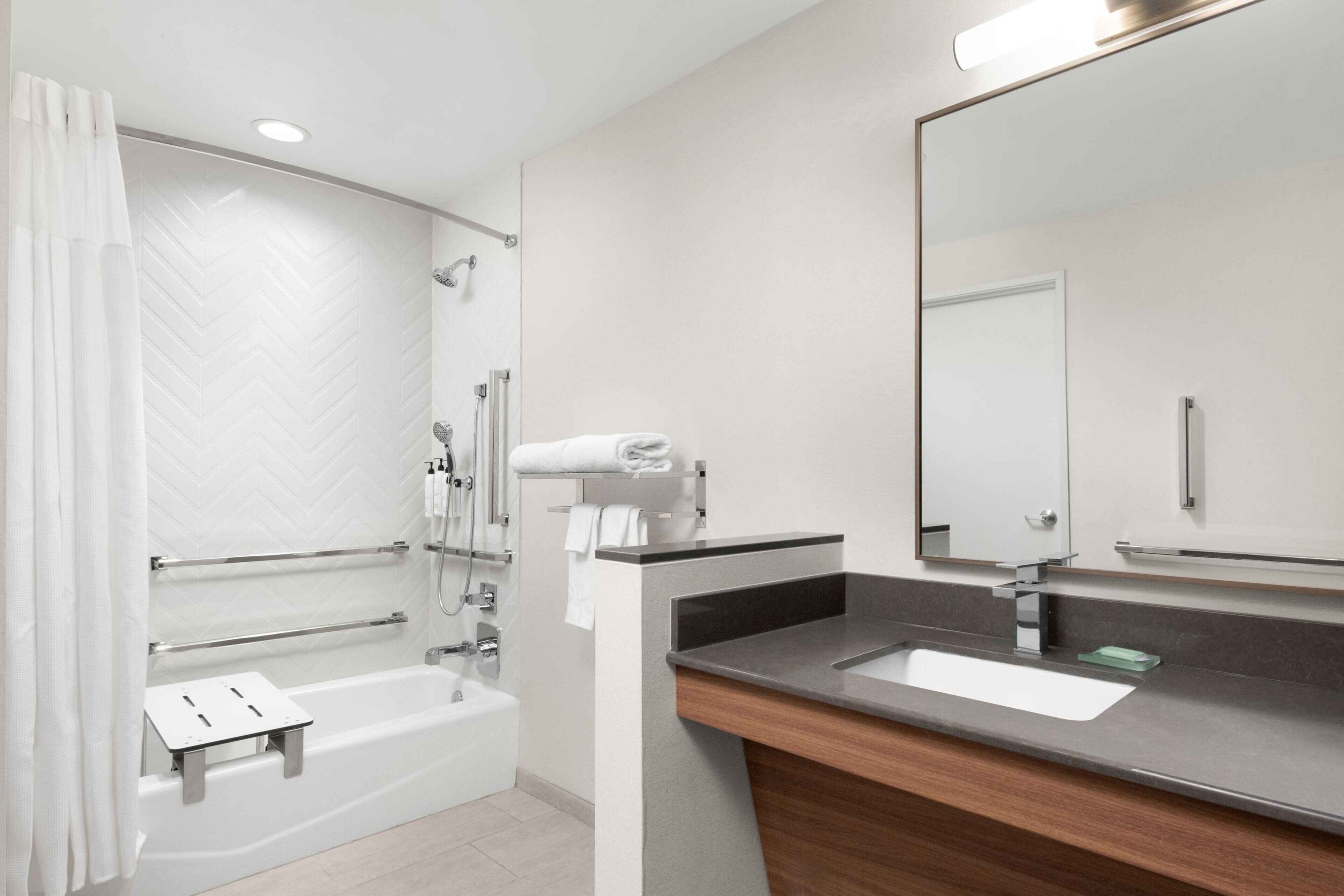 Un baño moderno con una bañera, un tocador con lavabo y un espejo grande.