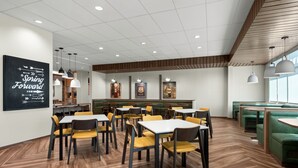 Een modern restaurant met houten vloeren, geel-groene zitplaatsen en een bord met de tekst 'Spring Forward' aan de muur.