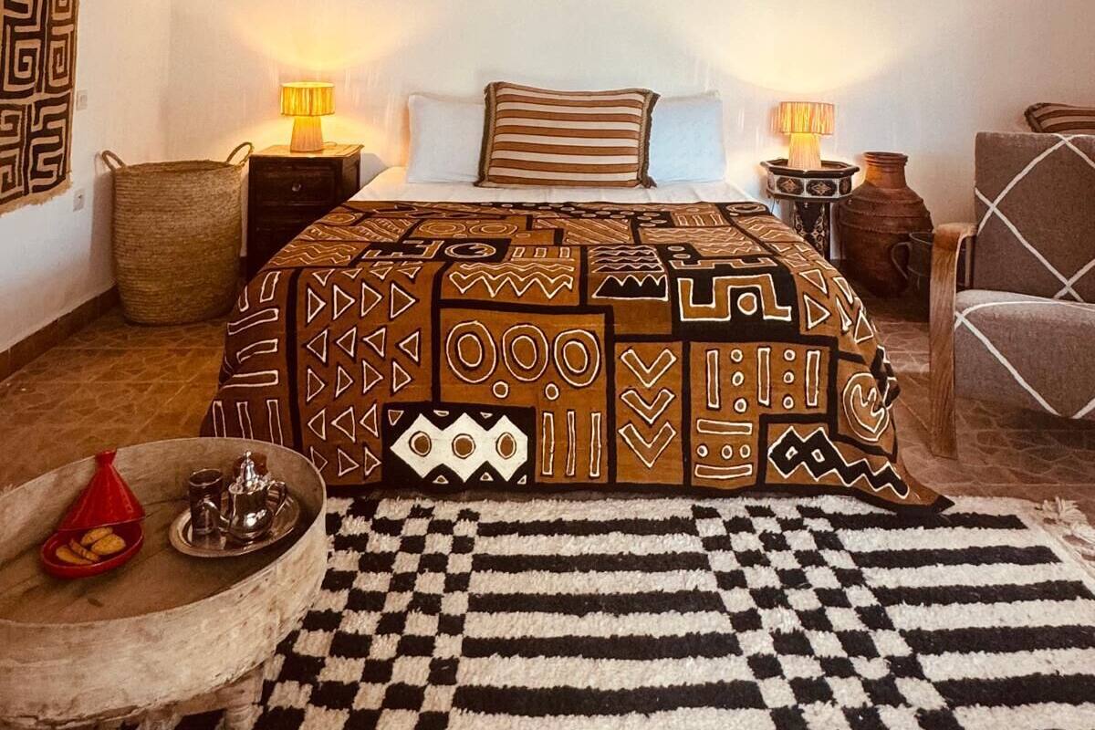 A traditional room with a wooden ceiling, a patterned bedspread, and a checkered rug.