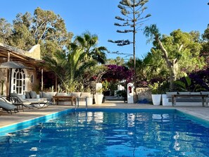 A pool area with lounge chairs and a stone building.