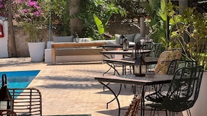 An outdoor patio with a pool, seating area, and hanging thatch umbrellas. - RIAD EUCALYPTUS, ETHNIC HOTEL (Essaouira)