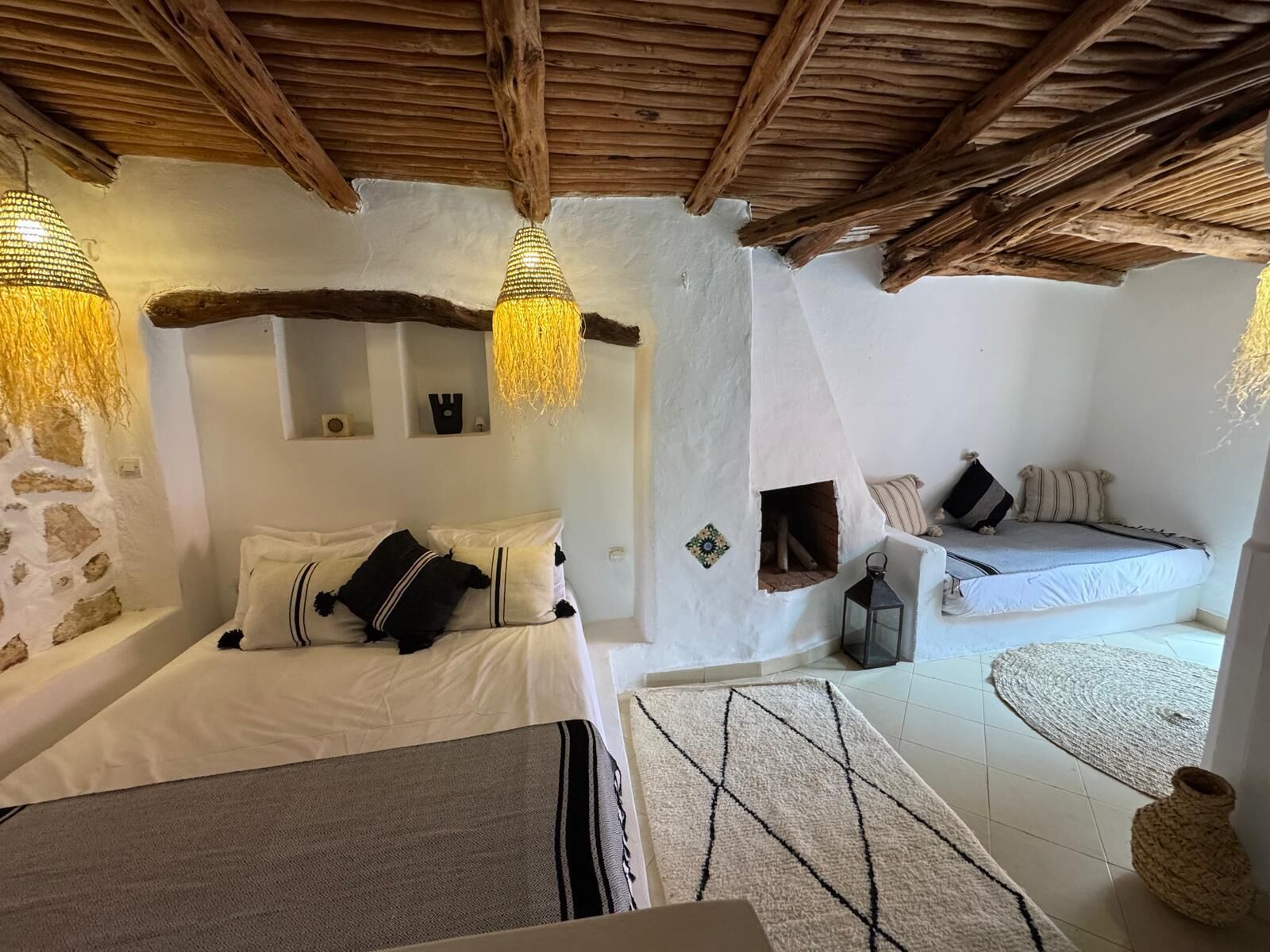 Een gezellige kamer met een bed, een bank en een klein tafeltje. Twee hanglampen en een houten plafond.