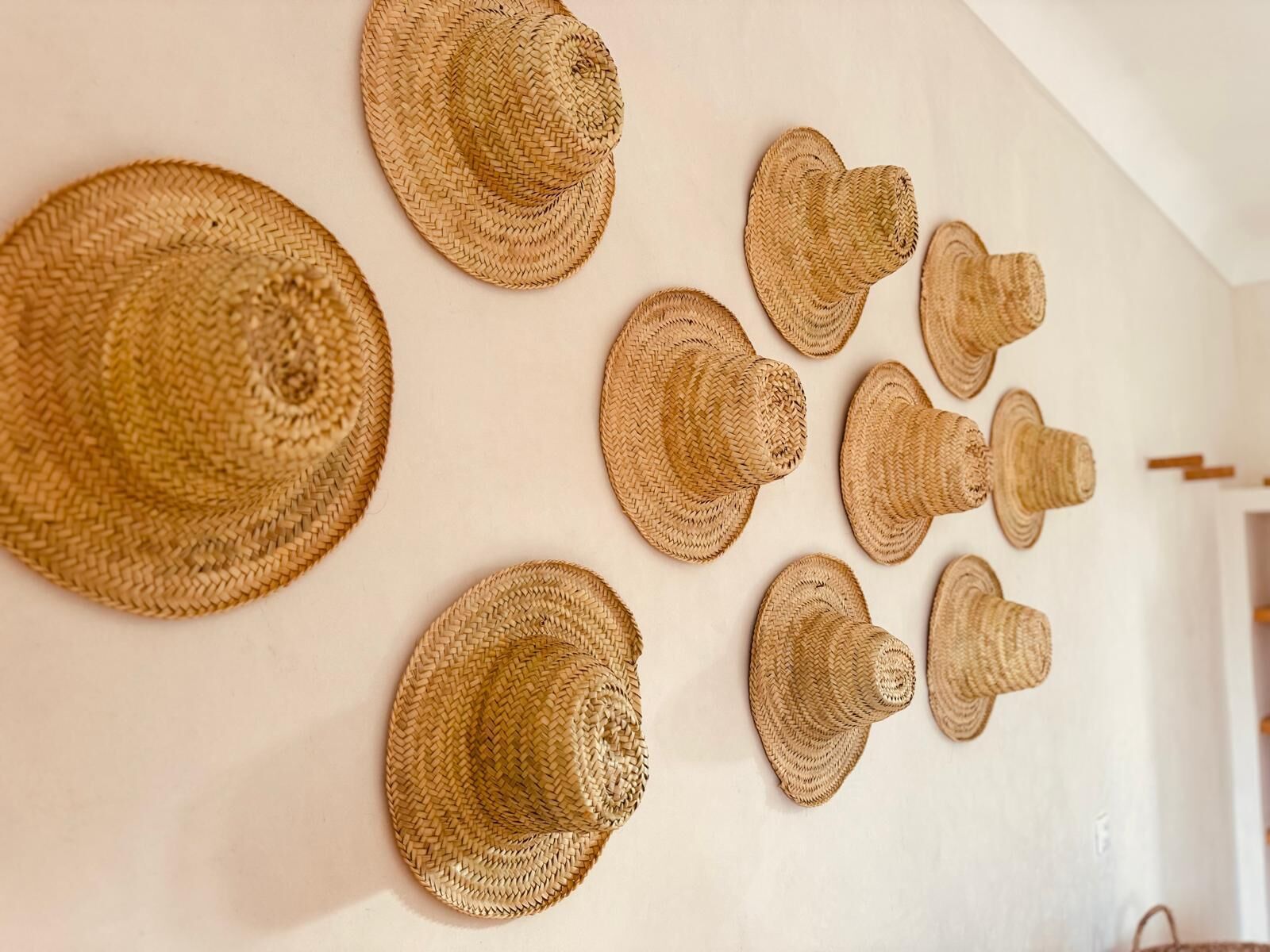 A wall with various woven hats displayed.