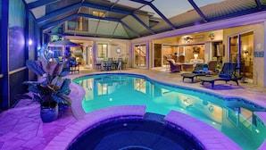 An indoor swimming pool with a glass ceiling, lounge chairs, and a dining area. - Intervillas Florida - Villa Valentina (Cape Coral)