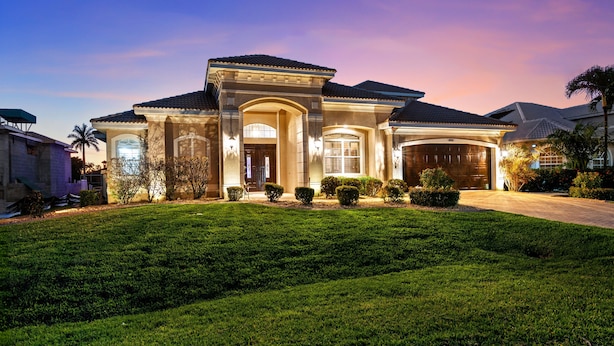 A large, two-story house with a well-maintained lawn and a driveway leading to the garage. - Intervillas Florida - Villa Valentina (Cape Coral)
