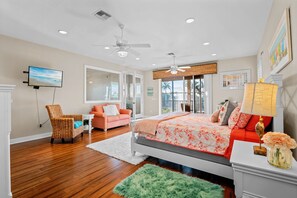 A bedroom with a bed, a chair, a sofa, a TV, and a window. - Intervillas Florida - Villa Valentina (Cape Coral)