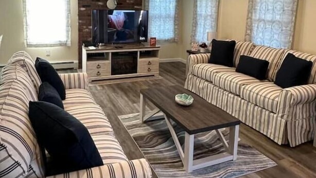 A living room with striped sofas, a coffee table, and a TV on a wooden cabinet.