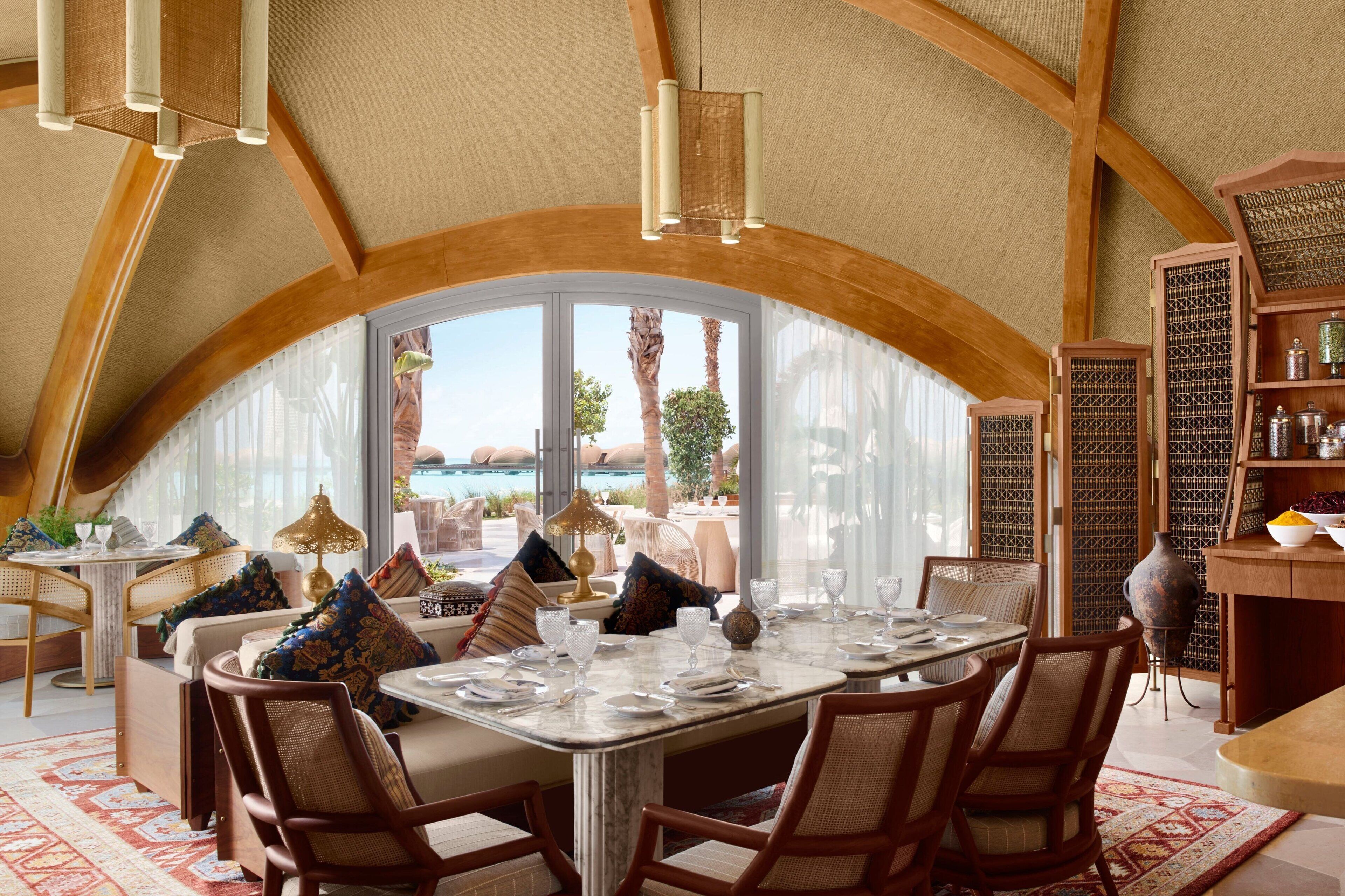 Zona pranzo con un'ampia finestra, travi in legno e vista sull'oceano.