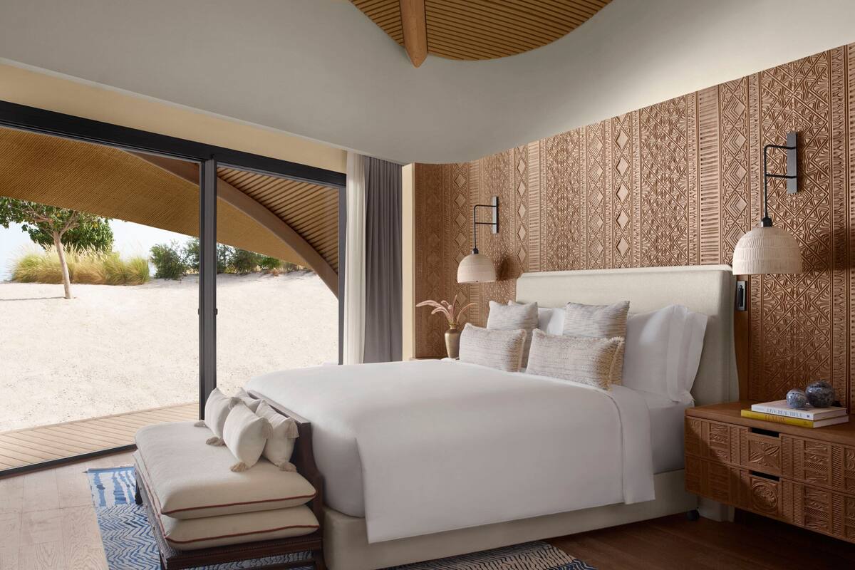A modern bedroom with a large bed, a wooden nightstand, and a patterned wall.