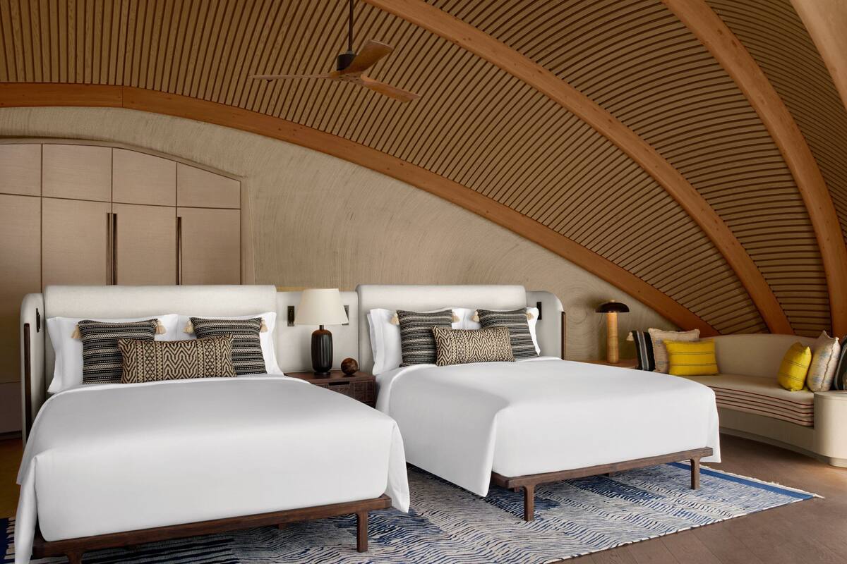 A bedroom with two beds, a sofa, and a ceiling fan.