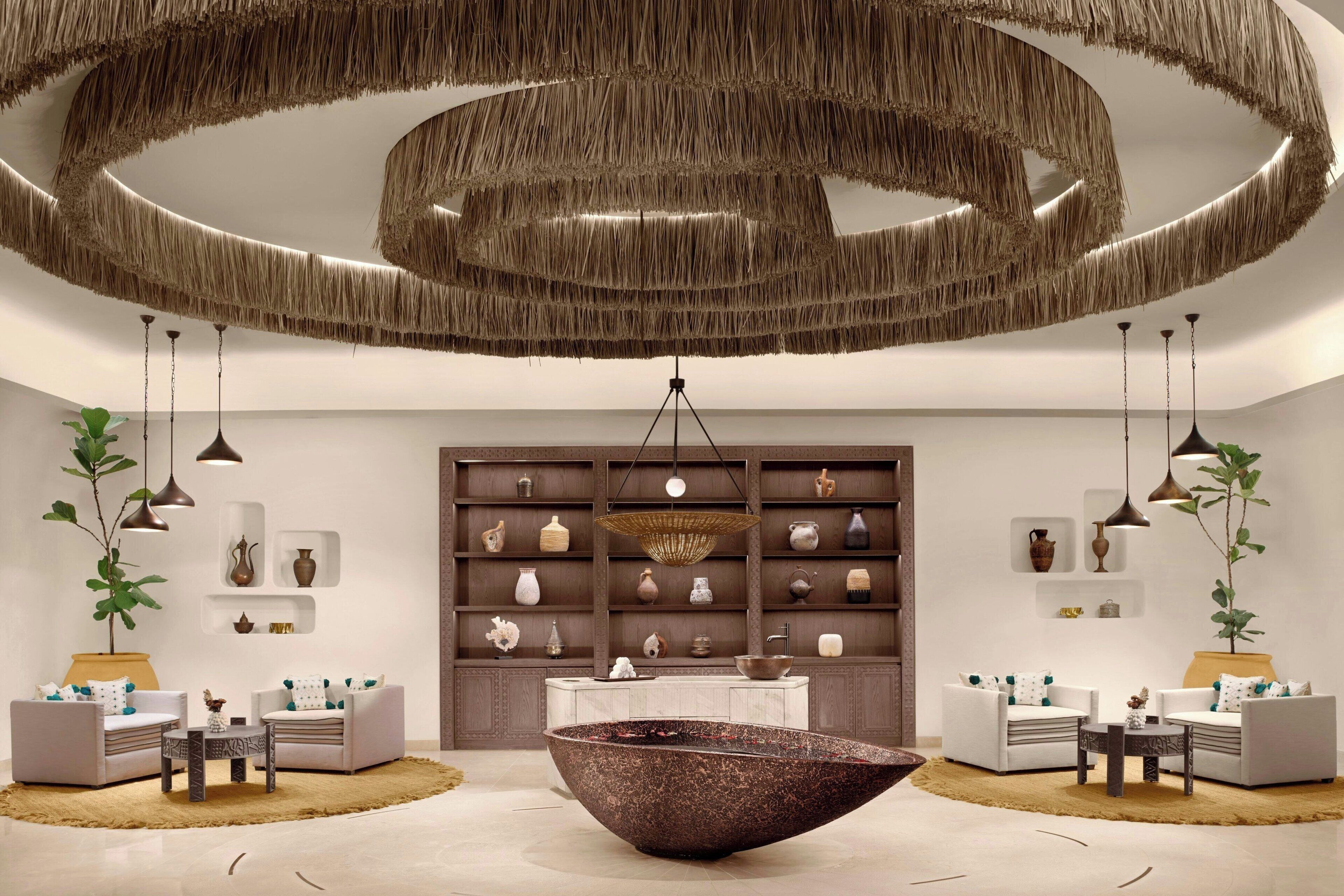 A modern interior with a central water feature, sofas, and a wall of decorative vases.