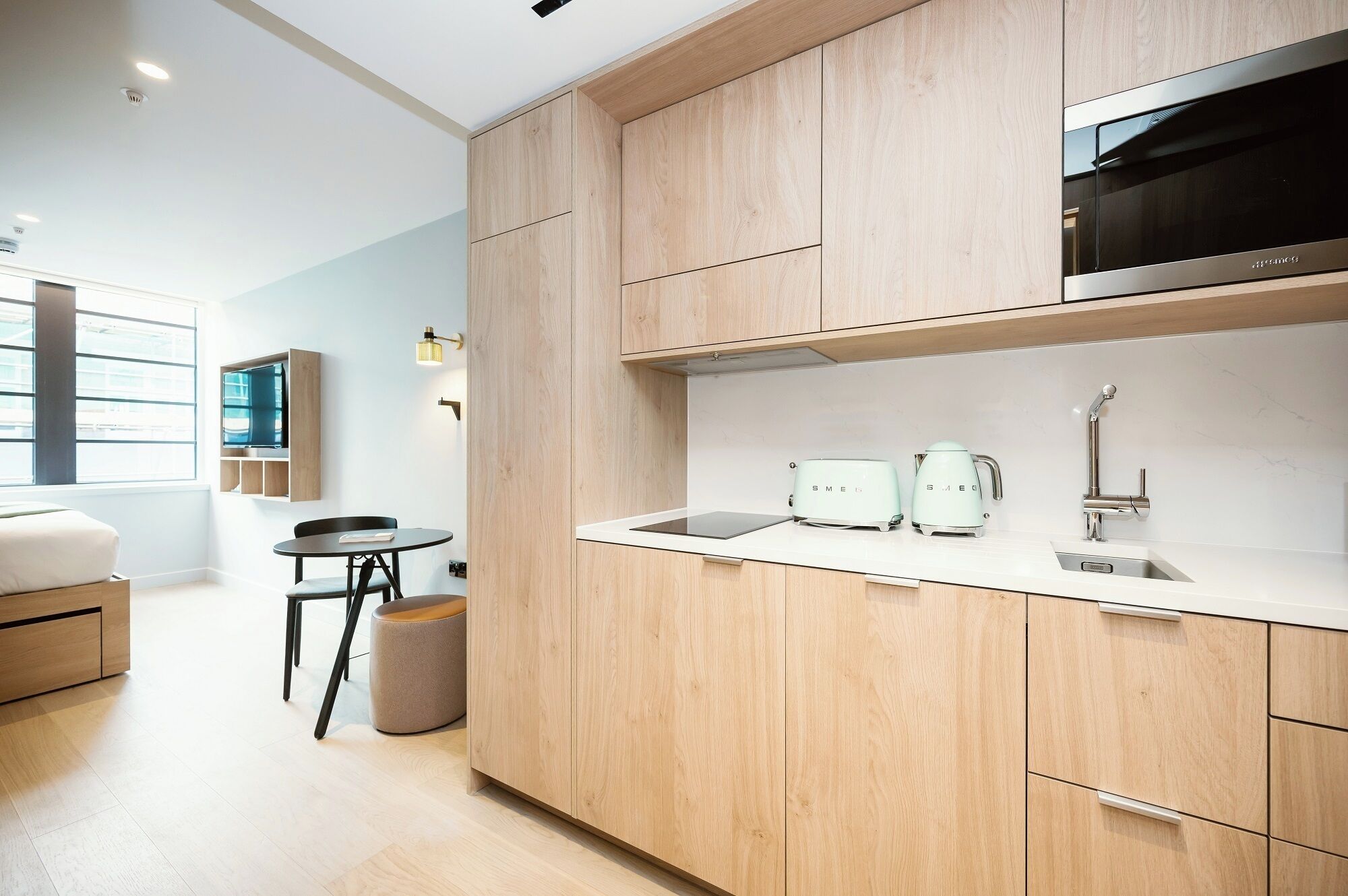 A modern kitchen with wooden cabinets, a stainless steel microwave, a sink, and a coffee maker.