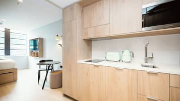 A modern kitchen with wooden cabinets, a stainless steel microwave, a sink, and a coffee maker.