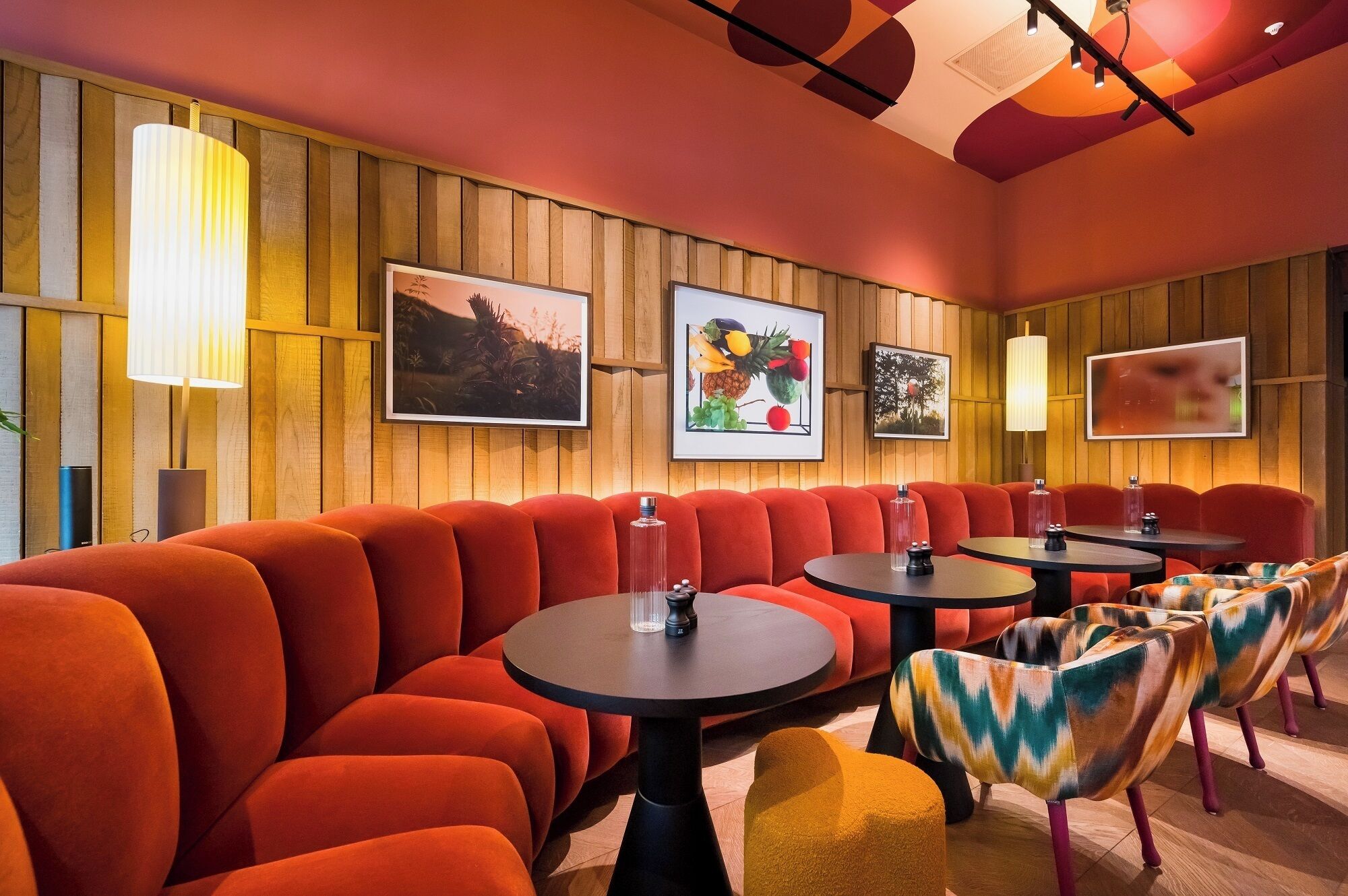 Eine moderne Lounge mit roten Sitzgelegenheiten, runden Tischen und Wandverkleidungen aus Holz.
