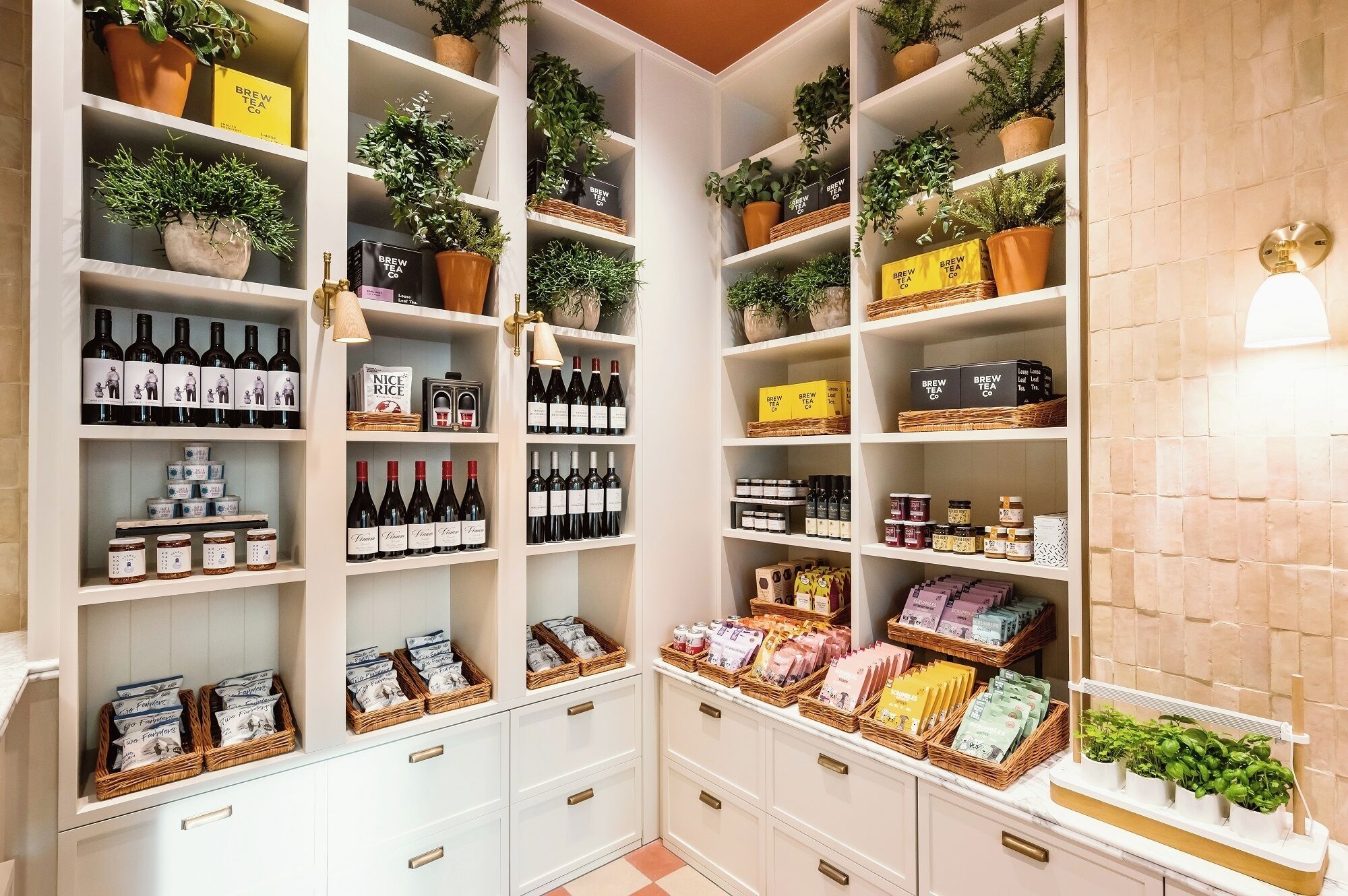 A well-organized storage area with shelves containing wine bottles, tea boxes, and wicker baskets.