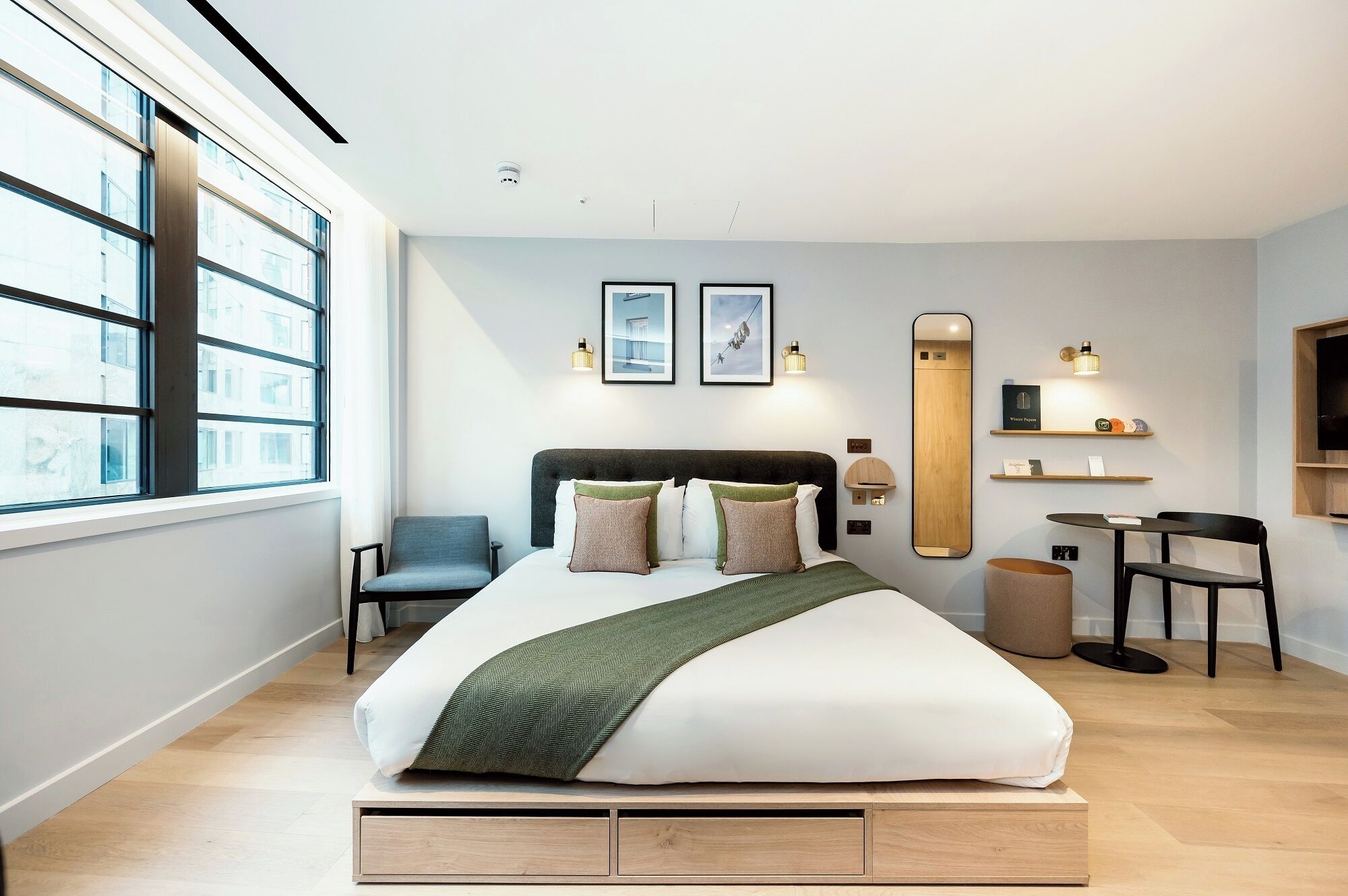 Een moderne hotelkamer met een bed, een stoel, een bureau en een groot raam.