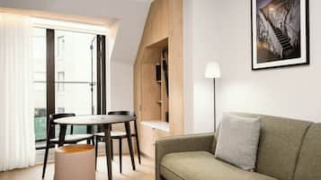 A modern living room with a round table, two chairs, a sofa, a lamp, and a framed picture on the wall.