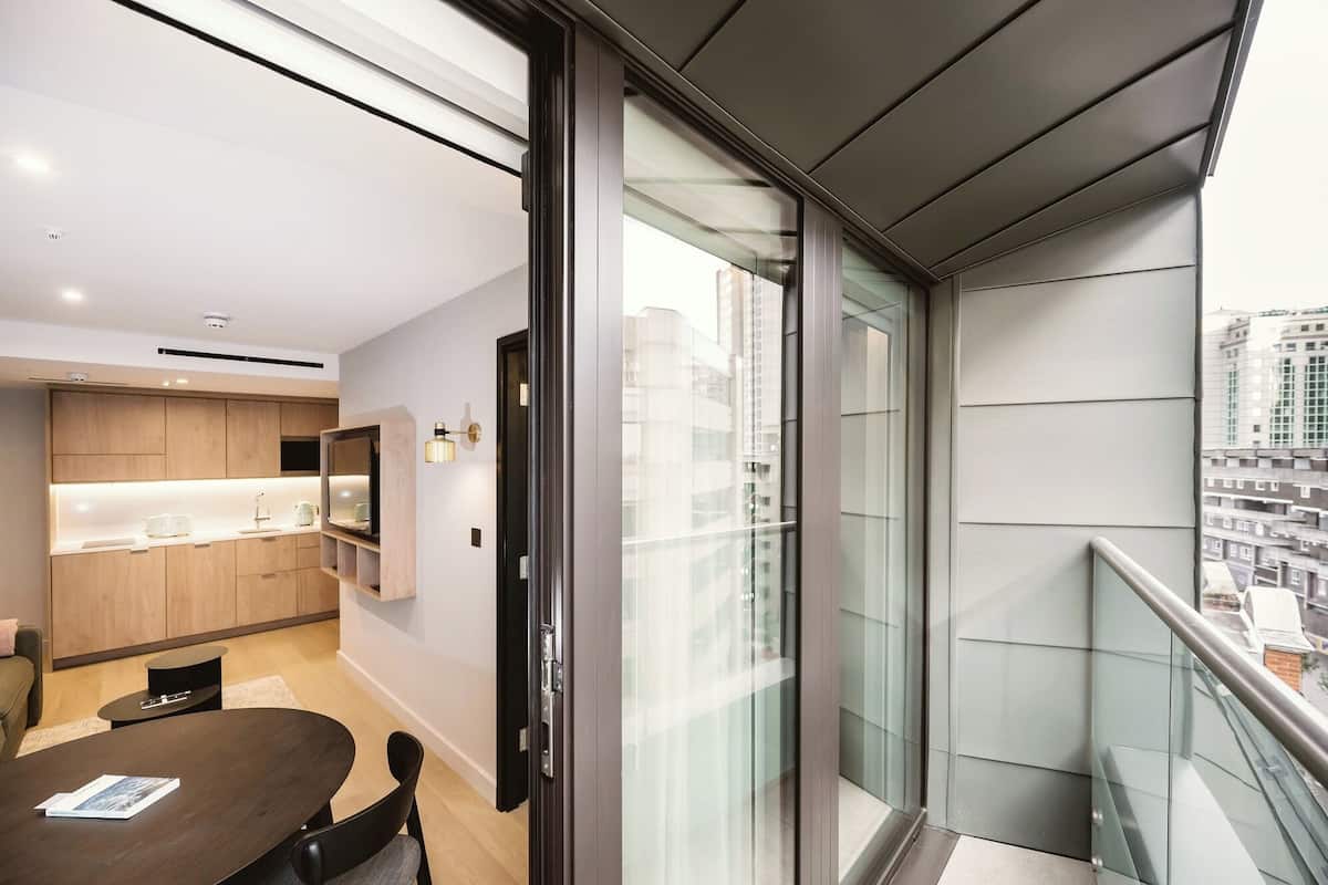 A modern apartment with a kitchen, dining area, and a balcony with a city view.