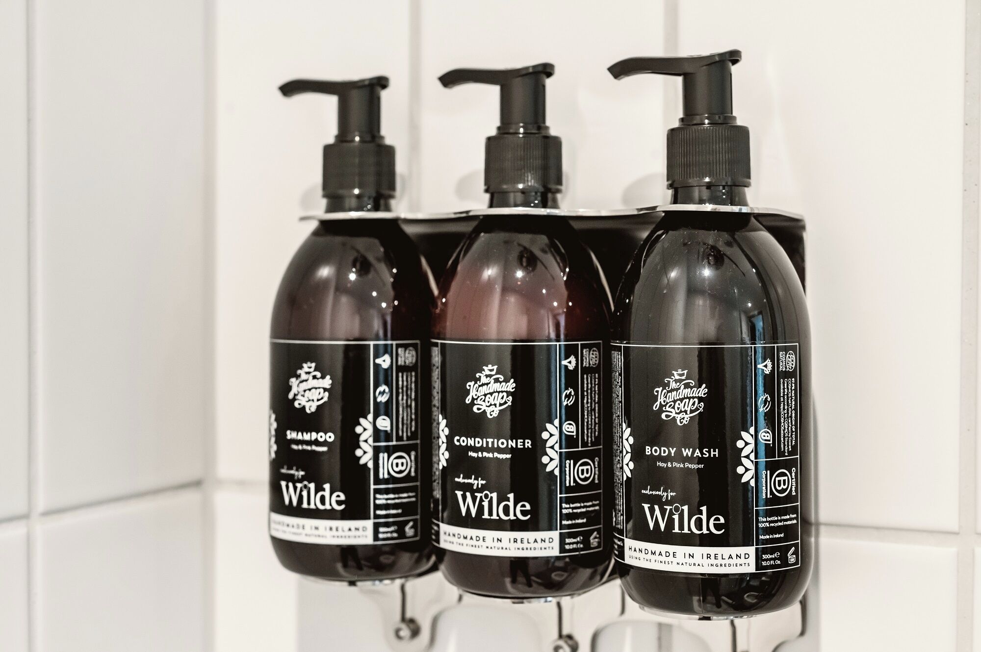 Tres botellas de productos de limpieza Wilde sobre una estantería blanca.