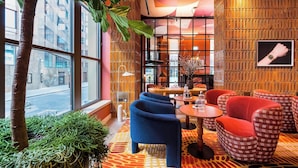 A modern interior with a large window, a tree, and a seating area with a patterned rug. - Wilde Aparthotels London Liverpool St.  (London)