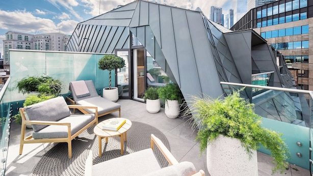 A modern rooftop terrace with seating, potted plants, and a city skyline view. - Wilde Aparthotels London Liverpool St.  (London)