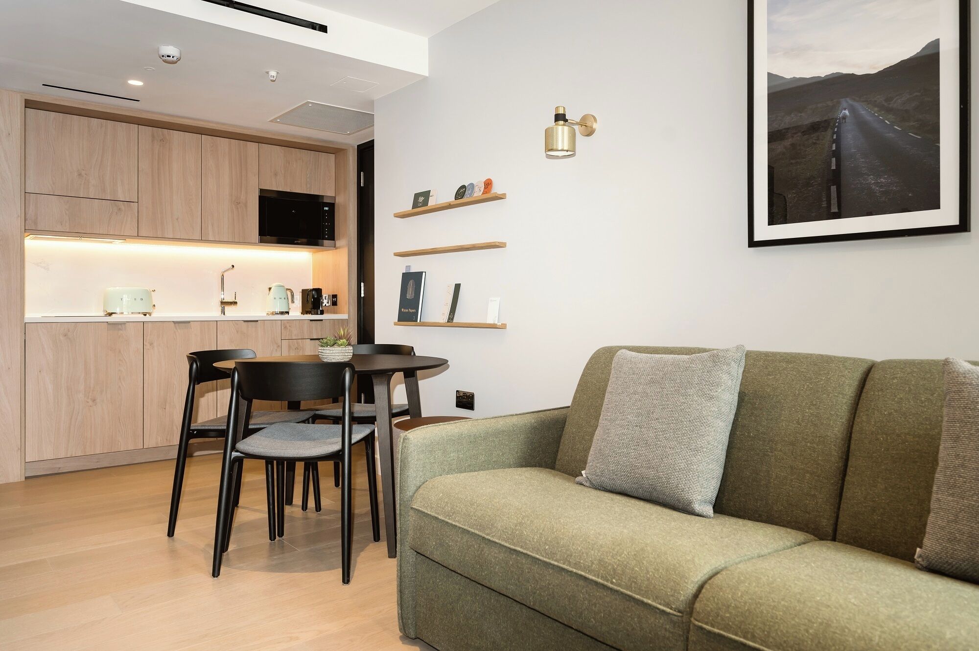 A modern living space with a kitchen, dining area, and a sofa with a cushion.