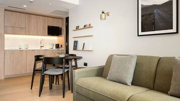 A modern living space with a kitchen, dining area, and a sofa with a cushion.