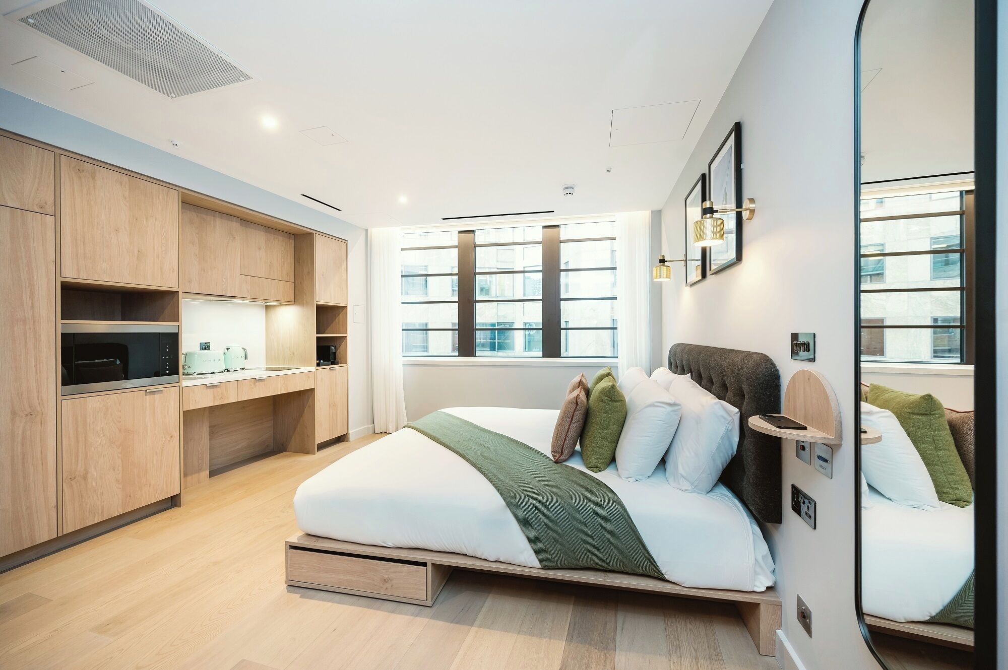A modern bedroom with a built-in wardrobe, a large window, and a bedside table with a lamp.